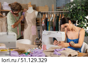 Young female dressmaker sewing while man working with mannequin. Стоковое фото, фотограф Яков Филимонов / Фотобанк Лори