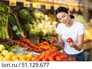 Woman carefully selects fresh tomatoes, standing near the counter in supermarket. Стоковое фото, фотограф Яков Филимонов / Фотобанк Лори