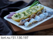 Fish herring, sliced into pieces and potatoes lie on a white plate with greens. Стоковое фото, фотограф Наталия Кирсанова / Фотобанк Лори
