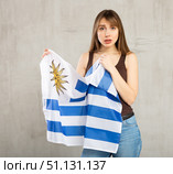Sad young woman holding flag of Uruguay against unicoloured background. Стоковое фото, фотограф Яков Филимонов / Фотобанк Лори