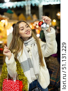 Portrait of dreamily happy girl with Christmas balls in her hands at a street fair in evening. Стоковое фото, фотограф Яков Филимонов / Фотобанк Лори