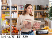 Girl looking at raw bbg sausage and raw pork chop in store. Стоковое фото, фотограф Яков Филимонов / Фотобанк Лори