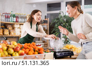Woman sells and puts candies in bag for young woman, puts them on scale and weighs fruits. Стоковое фото, фотограф Яков Филимонов / Фотобанк Лори