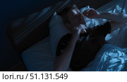 Young man unable to sleep, suffering from insomnia lies awake in bed at night. Стоковое видео, видеограф Arsenii Palivoda / Фотобанк Лори