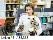 Woman with Yorkshire terrier scanning barcodes on dog food with smartphone in pet store. Стоковое фото, фотограф Яков Филимонов / Фотобанк Лори