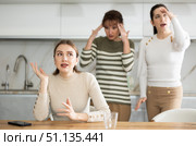 Upset middle-aged woman sitting at the kitchen table with her back to women quarreling to her. Стоковое фото, фотограф Яков Филимонов / Фотобанк Лори