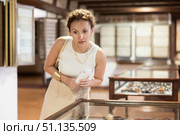 Woman examining antique artifacts within glass vitrine in museum. Стоковое фото, фотограф Яков Филимонов / Фотобанк Лори