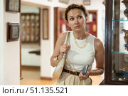Woman curiously observing antique artifacts in historical museum. Стоковое фото, фотограф Яков Филимонов / Фотобанк Лори