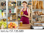 Woman vendor selling canned olives in grocery department of supermarket. Стоковое фото, фотограф Яков Филимонов / Фотобанк Лори