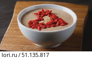 Chestnut cream dessert spotlighting goji berry heart design, quinoa garnish, presented in white ceramic bowl atop rustic wooden surface. Стоковое AI-видео, аниматор Юрий Поздников / Фотобанк Лори