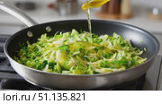 Golden olive oil is poured over a mix of chopped vegetables including brussel sprouts, cabbage, and herbs in a stainless steel pan on a gas stovetop. Стоковое AI-видео, аниматор Юрий Поздников / Фотобанк Лори