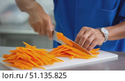 Professional chef in blue uniform slicing fresh carrots into thin julienne strips on white cutting board, preparing culinary ingredients with precision. Стоковое AI-видео, аниматор Юрий Поздников / Фотобанк Лори