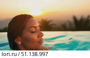 Relaxing by an infinity pool, a woman enjoys the breathtaking sunset over the mountains. Стоковое AI-видео, аниматор Данила Большаков / Фотобанк Лори