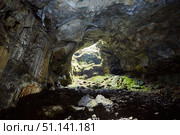Dark cave view from inside with a lumen. Stalactites and stalagmites inside the stone grotto. Colorful stones in the cave. Lighting electricity beauty of the cave. (2019 год). Стоковое фото, фотограф Наталия Кирсанова / Фотобанк Лори