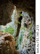 Dark cave view from inside with a lumen. Stalactites and stalagmites inside the stone grotto. Colorful stones in the cave. Lighting electricity beauty of the cave. (2019 год). Стоковое фото, фотограф Наталия Кирсанова / Фотобанк Лори