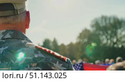 A respectful event honoring veterans unfolds with flags and attendees gathered together. Стоковое AI-видео, аниматор Данила Большаков / Фотобанк Лори