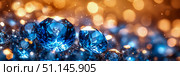 Vibrant blue faceted gemstones resting on dark, shimmering ground, illuminated by brilliant backdrop of orange and gold defocussed lights with delicate stardust effects. Стоковое AI-изображение, AI-художник Данила Большаков / Фотобанк Лори