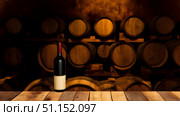 Red wine bottle on wooden table in cellar with wine barrels background. Стоковое AI-изображение, AI-художник Дмитрий Нечаев / Фотобанк Лори