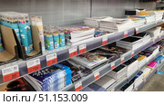 Shelves in a store with a range of school and art supplies. In the foreground are sets of colored pencils in cylindrical plastic tubes with a transparent lid. The pencils are packed in 12 pieces and have a compact format, convenient for storage and transportation. Nearby are neatly stacked stacks of notebooks and sketchbooks of different formats - softcover, paperclip and spiral. The covers are decorated with bright drawings, abstractions, animal illustrations and fantasy images. On the bottom shelf are sketchbooks with white and black sheets, sketch pads and art notebooks. The price tags indicate discounts and promotions, which emphasizes the attractiveness of the offer. The photo is well lit, with clear detail, suitable for online stationery stores, catalogs of school supplies, advertising materials for stores and educational projects. Редакционное фото, фотограф Анна Кривицкая / Фотобанк Лори