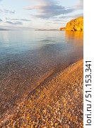 Scenic sunset landscape of Baikal Lake. View of clear transparent water on pebble beach of Small Sea and rocky coast of Olkhon Island on quiet August evening. Picturesque seascape. Natural background. Стоковое фото, фотограф Виктория Катьянова / Фотобанк Лори