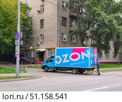Грузовик закрывает дверцы фургона службы доставки Ozon возле шлагбаума. Доставка в пункт выдачи заказов. Редакционное фото, фотограф Мария Сергеева / Фотобанк Лори