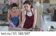 Female seamstress discussing with female client the drawing of future dress on laptop. Стоковое видео, видеограф Яков Филимонов / Фотобанк Лори