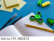 Back to School Supplies with Notebook, Fidget Spinner, Sticky Notes and Pens on Blue Background.Flat lay composition of school supplies on a blue desk. Open squared notebook with pencil, pens, sticky notes, colorful fidget spinner and highlighters. Creative back to school background, education concept, stationery for students and kids. Стоковое фото, фотограф Анастасия Мерчик / Фотобанк Лори