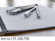 Open Notebook with Black Pens on Grid Paper Minimal Back to School Concept. composition with an open squared notebook and several black gel pens on a white desk. Clean layout for studying, writing, education, or office work. Perfect background for learning, school, or stationery themes. Стоковое фото, фотограф Анастасия Мерчик / Фотобанк Лори