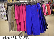 Shows a rack of women's clothing in a store. The hangers are filled with bright styles - blue wide trousers, pink dresses or tunics, grey items, and leopard print clothing. In the left background, white T-shirts with patterns are visible, while on the right, striped sweaters and pink jackets. The photo conveys the atmosphere of a clothing supermarket, bright colours and a variety of styles. Suitable for use in fashion, retail, shopping and lifestyle themes. Стоковое фото, фотограф Анна Кривицкая / Фотобанк Лори