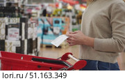 A woman in a supermarket looks at a receipt from purchases. Стоковое видео, видеограф Igor Skripachev / Фотобанк Лори