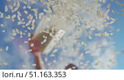 A man carefully empties a substantial quantity of uncooked white rice from a container into a transparent glass in the fresh air. Стоковое видео, видеограф Strunov David / Фотобанк Лори