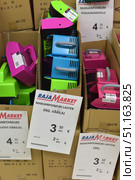 A display at the Finnish Raja Market with brightly coloured plastic berry pickers. The image shows boxes filled with the devices in different colours – pink, green and blue. These devices are called marjanpoimuri (berry pickers) and are used to pick wild berries such as blueberries or lingonberries. The devices have comfortable handles and teeth for easy separation of berries from bushes. In the foreground are price tags with inscriptions in Finnish: the cost is 3.50 euros each and 2.82 euros for several. The atmosphere of the photo conveys the atmosphere of a hardware store with practical and useful products for the summer house, forest and gardening. (2015 год). Редакционное фото, фотограф Анна Кривицкая / Фотобанк Лори