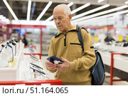 elderly man examines tablet computer in showroom of electronics store. Стоковое фото, фотограф Татьяна Яцевич / Фотобанк Лори