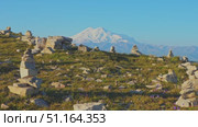 4k, panoramic view of the Bolshoy Bermamyt plateau with stone turrets built on a grassy slope, with the snow-capped peaks of Mount Elbrus in the background, at early morning, Stavropol Krai, Russia. Стоковое видео, видеограф Сергей Богомяко / Фотобанк Лори