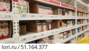 Supermarket shelf with dairy products in cardboard boxes and plastic bottles. Different brands of milk are visible, including "Domik v Derevne" and "Klever", with fat content of 1.5% and 3.2%. The price tags indicate prices in rubles. The shelves are partially filled, in some places there are empty cells with cardboard dividers. The photo shows a modern store interior, everyday food products and the consumer environment. (2018 год). Редакционное фото, фотограф Анна Кривицкая / Фотобанк Лори