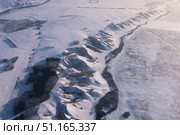 Aerial view shows a vast, pristine snowcovered landscape with hills and a winding river. Mountainous hilly snow-covered ridge imho aerial view. Minino, Krasnoyarsk. Стоковое фото, фотограф Владимир Разгуляев / Фотобанк Лори