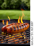 Sizzling bratwurst grilling over flaming charcoal, releasing appetizing aroma during backyard barbecue weekend gathering. Стоковое AI-изображение, AI-художник Юрий Поздников / Фотобанк Лори
