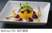 Corn cake gourmet style, accompanied by fresh greens, orange croutons, dark berries, drizzled with red, yellow sauces, balsamic glaze on white plate, dark textured background. Стоковое AI-видео, аниматор Юрий Поздников / Фотобанк Лори