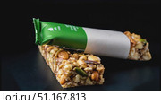 Granola bars displaying mixed nuts and seeds, partially peeling from green wrappers, gently rotating against dark monochromatic background. Стоковое AI-видео, аниматор Юрий Поздников / Фотобанк Лори