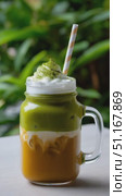 Chilled matcha green tea latte garnished with whipped cream, paper straw in glass mug against soft natural backdrop. Стоковое AI-видео, аниматор Юрий Поздников / Фотобанк Лори