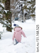 Rear view of a little girl dressed in warm cozy clothes walking through a winter park or forest with knee-deep snow. Peaceful, chilly winter nature atmosphere. High quality photo. Стоковое фото, фотограф Ирина Михайличенко / Фотобанк Лори