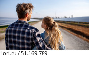 Father and daughter looking at solar panels. Solar farm and sunlight at sunset. Solar energy for green energy. Sustainable renewable energy. Photovoltaic power plant or solar park. Energy sustainability. Стоковое AI-изображение, AI-художник ALLA YURTAYEVA / Фотобанк Лори