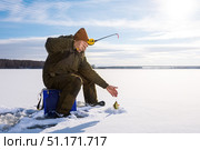 Man ice fishing in frozen lake in winter sunny day. Ice fishing adventure, active hobby. Стоковое фото, фотограф Сергей Чуйко / Фотобанк Лори