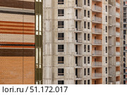 Фасад строящегося многоэтажного дома с кирпичной облицовкой рядом с бетонным каркасом другого здания. Стоковое фото, фотограф Кирилл Сиротюк / Фотобанк Лори