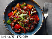 Sweet sour pork with colorful peppers, mixed vegetables served in a black bowl on dark concrete background. Traditional Chinese dish. Close-up. The meat pieces in a brown sauce glaze. Sichuan cuisine. Стоковое AI-изображение, AI-художник Марина Демидюк / Фотобанк Лори