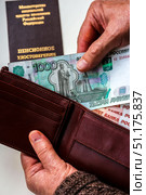 Woman's hands holding wallet with russian rubles, russian pension certificate in background. Russian translation - Ministry of Social Protection of Population of Russian Federation. Pension Certificate. Стоковое фото, фотограф Denis Vostrikov / Фотобанк Лори