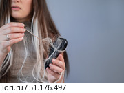Young woman worried about hair loss hairbrush full of broken strands showing early signs of alopecia and hair breakage. Стоковое фото, фотограф Svetlana Golovco / Фотобанк Лори