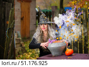 Halloween a woman with a magic bowler hat witch conjures, performs witchcraft in a creepy old magical house. Стоковое фото, фотограф Лазаренко Светлана / Фотобанк Лори