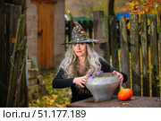 Halloween girl with a magic bowler hat in a witch hat performs witchcraft against an old creepy background. Стоковое фото, фотограф Лазаренко Светлана / Фотобанк Лори