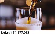 Medium close-up of a straight-sided pint filled with light-amber lager; dense white foam against a cool blue/black background. 4K MP4, no people. Стоковое AI-видео, аниматор Владислав Войтов / Фотобанк Лори